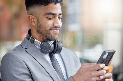 Buy stock photo Business man, phone typing and city of a professional with headphones watching a video. Urban, smile and Indian male person with work travel, mobile and happiness with cellphone web and mockup