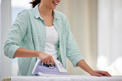 Buy stock photo Shot of a happy woman ironing her clothing