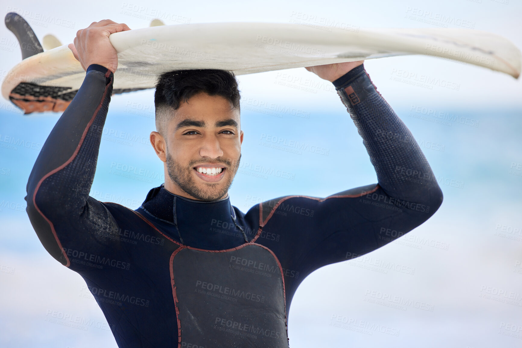 Buy stock photo Shot of a young man holding a surfboard at the beach