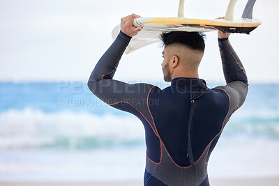 Buy stock photo Shot of a young man holding a surfboard at the beach