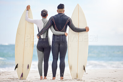 Buy stock photo Shot of a young couple holding surfboards at the beach