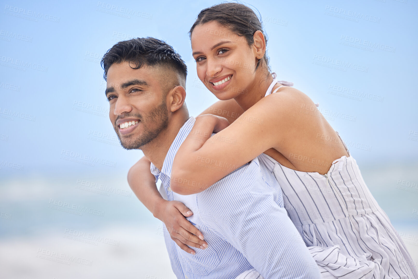 Buy stock photo Couple, happy and piggyback on beach for picnic, vacation and relax in summer by nature with love. Man, woman and hug by ocean blue sky in Portugal for adventure, holiday and freedom with smile