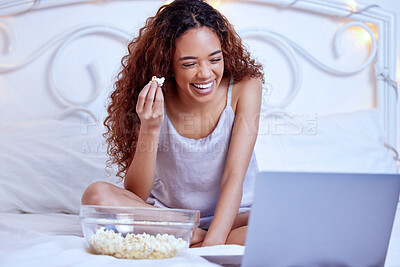 Buy stock photo Shot of a woman laughing while lying on her bed with her laptop and a bowl of popcorn