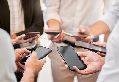 Buy stock photo Cropped shot of an unrecognizable group of businesspeople huddled together in the office and using their cellphones