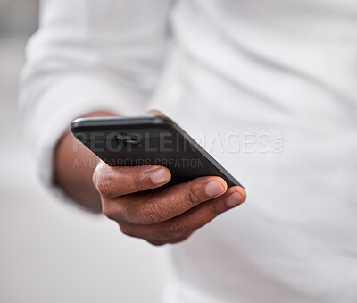 Buy stock photo Cropped shot of an unrecognizable businessman standing alone in the office and using his cellphone