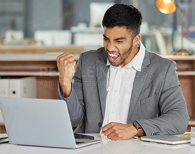 Buy stock photo Shot of a young businessman cheering while using a laptop in a modern office
