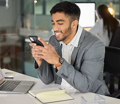 Buy stock photo Young businessman, phone and social media in office for chat, email and online research at desk. Happy consultant, networking and mobile app in workplace for lunch break, internet and communication