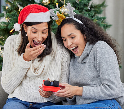 Buy stock photo Shot of two young women opening up gifts during Christmas time at home