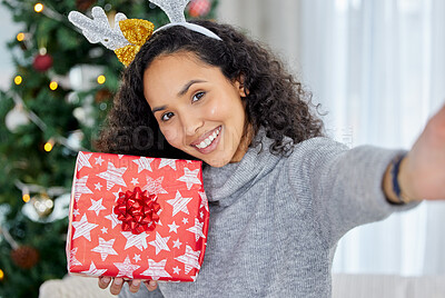 Buy stock photo Shot of a young woman holding up gifts during Christmas time at home