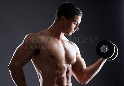 Buy stock photo Shot of an athletic man lifting dumbbells against a dark background
