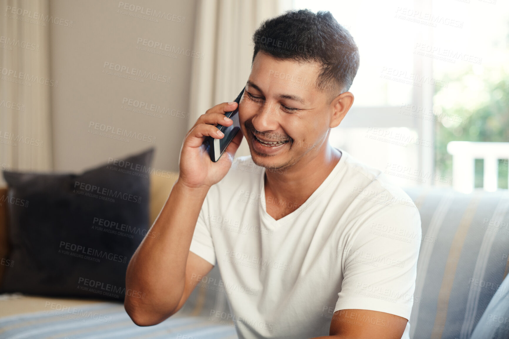 Buy stock photo Happy, man and talking with phone at house couch to relax, communication and contact on break by networking. Smile, male person and mobile discussion, laughing and funny joke in living room sofa