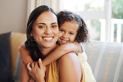 Buy stock photo Shot of an adorable young girl hugging her mother in the living room at home