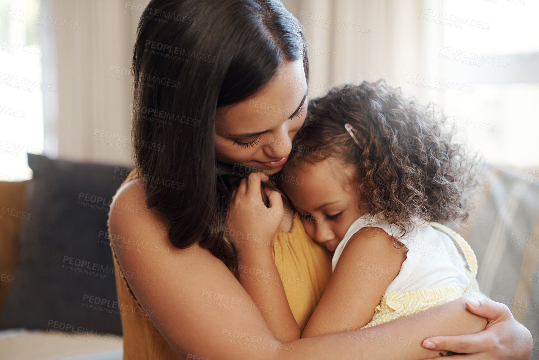 Buy stock photo Shot of an adorable young girl hugging her mother in the living room at home