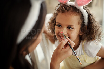 Buy stock photo Shot of a woman painting her daughters face during the easter holiday