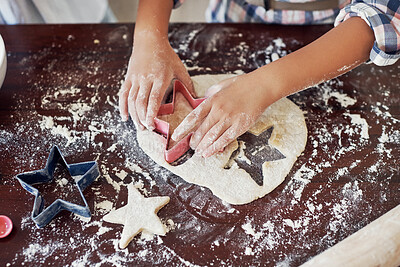 Buy stock photo Cropped shot of an unrecognizable girl using a cookie cutter while making cookies at home