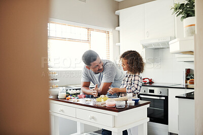 Buy stock photo Shot of a sweet little girl baking with her father at home in the kitchen