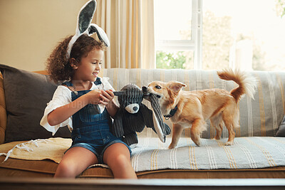 Buy stock photo Shot of an adorable young girl sitting on the sofa at home and playing with her dog
