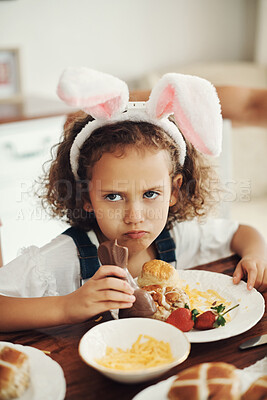 Buy stock photo Shot of an adorable young girl sitting alone and sulking while eating chocolate instead of breakfast at home
