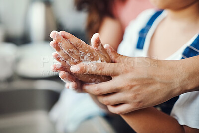 Buy stock photo Cropped shot of an unrecognizable woman helping her daughter wash her hands in the kitchen sink at home
