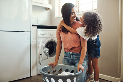 Buy stock photo Shot of an adorable young girl hugging her mother while helping her with the laundry at home