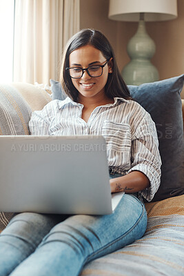 Buy stock photo Cropped shot of an attractive young woman using her laptop while relaxing on a sofa at home
