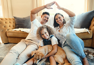 Buy stock photo Shot of a young family sitting on the floor in the living room at home and bonding with their dog