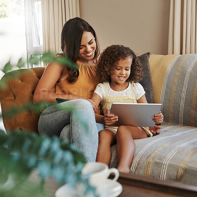 Buy stock photo Shot of an attractive young woman and her daughter sitting on the sofa at home and using technology