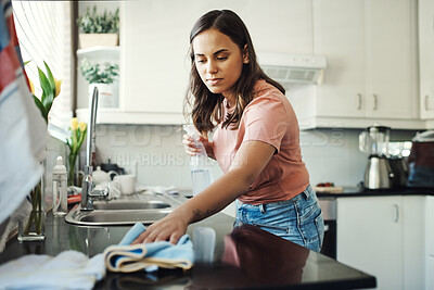 Buy stock photo Shot of an attractive young woman using a cloth to clean the kitchen counters at home