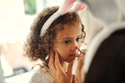 Buy stock photo Shot of a woman painting her daughters face during the easter holiday