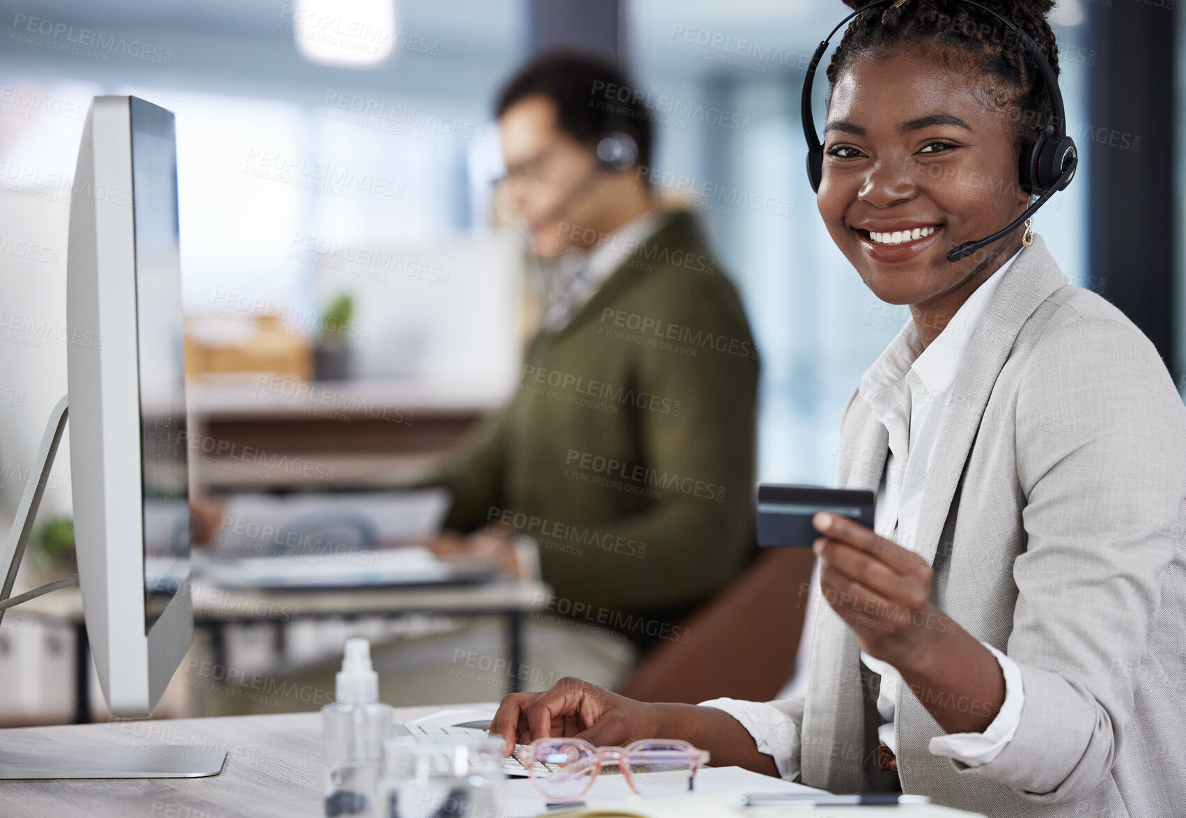 Buy stock photo Shot of a young female call center agent holding a credit card at work