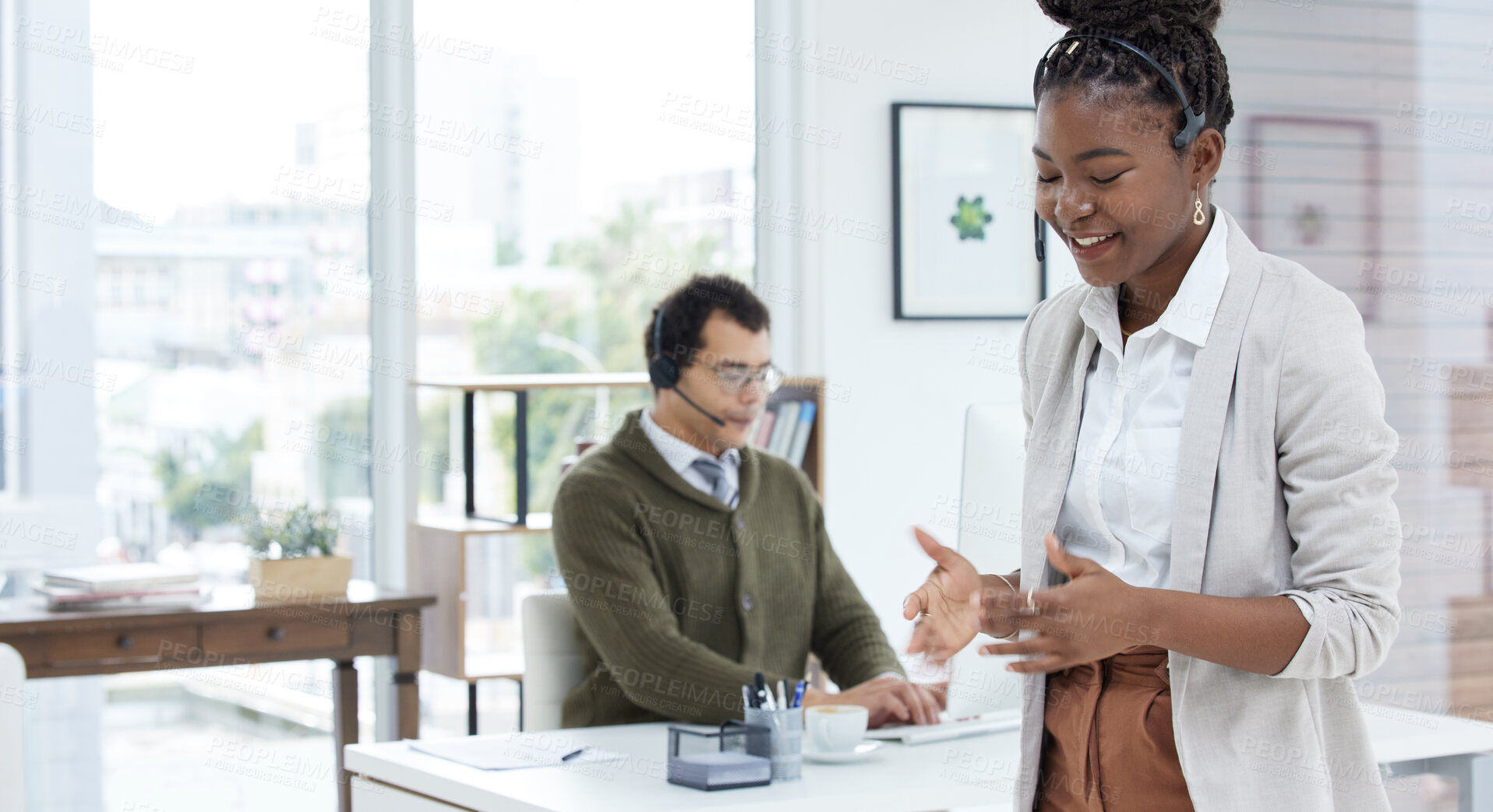 Buy stock photo Shot of a young businesswoman wearing a headset while working in an office with her colleague in the background