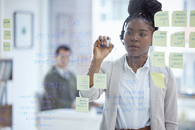 Buy stock photo Shot of a young businesswoman wearing a headset while brainstorming with notes on a glass wall in an office