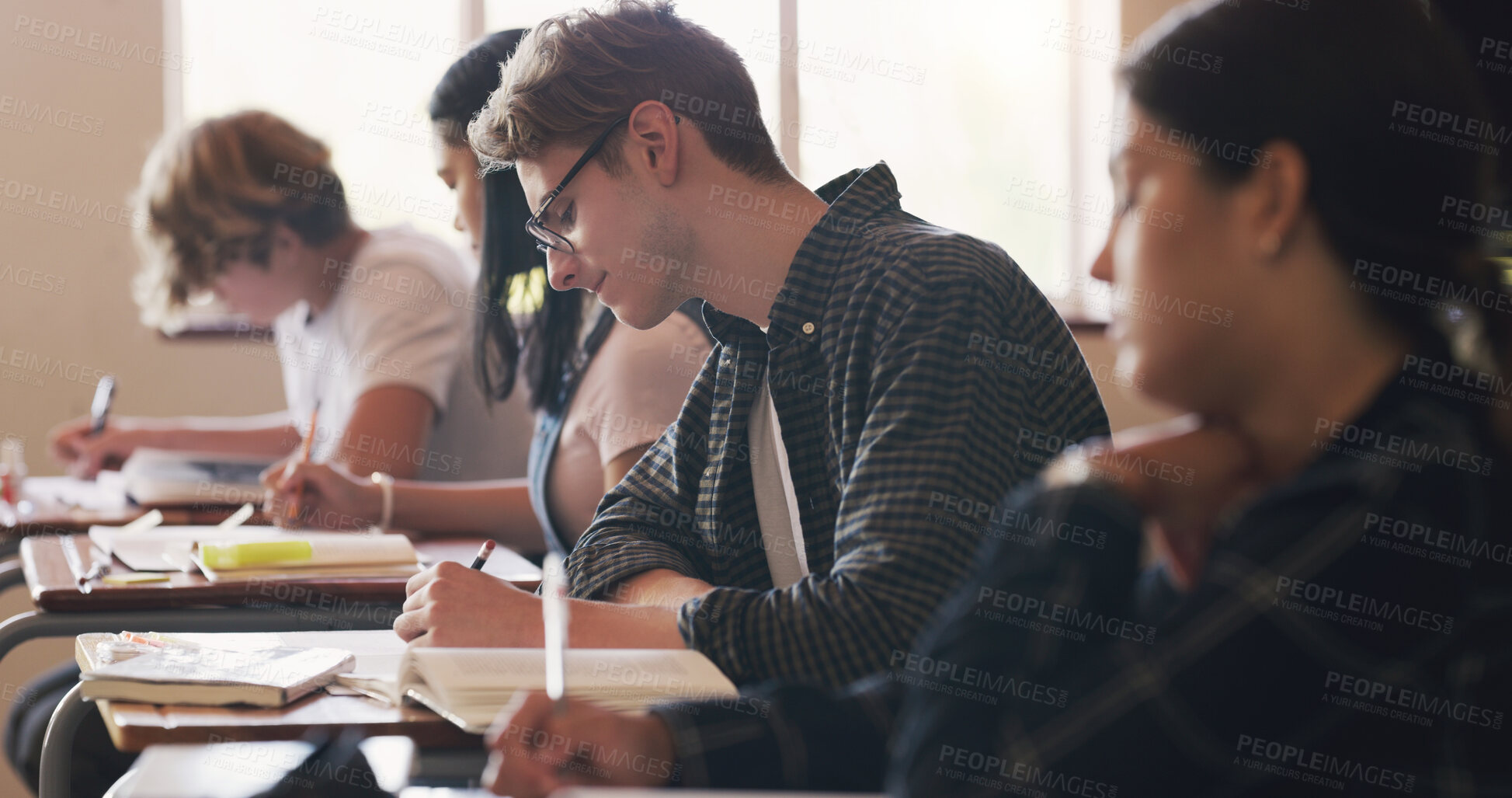 Buy stock photo Shot of teenagers writing an exam in a classroom