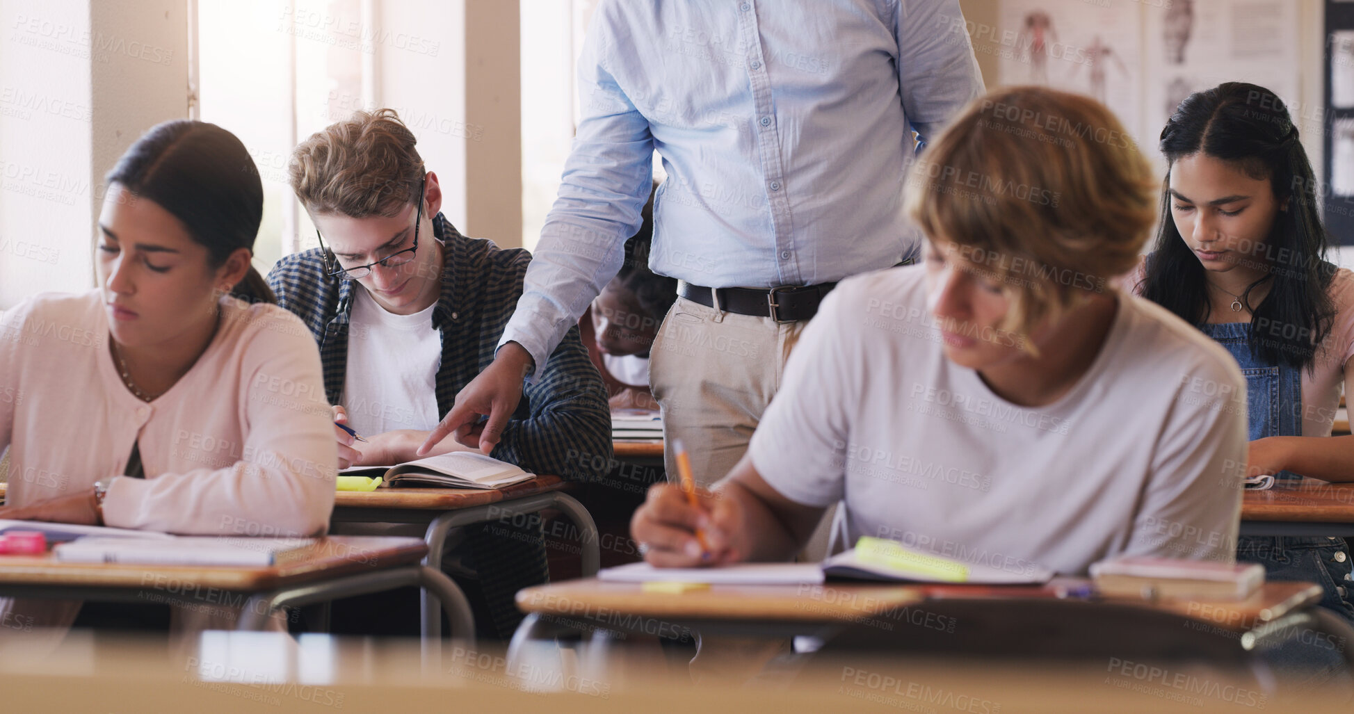 Buy stock photo Shot of teenage boy asking his teacher for help during an exam in a classroom