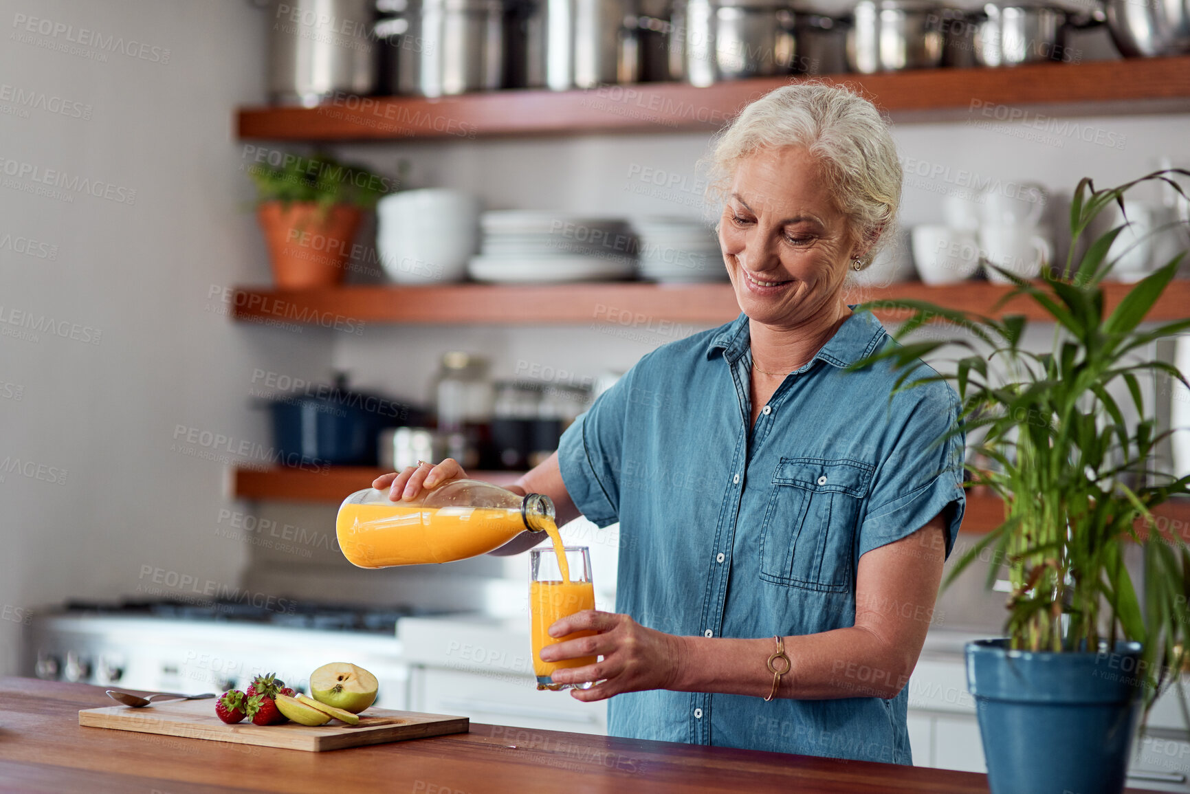 Buy stock photo Glass, juice and elderly woman at kitchen counter for breakfast, nutrition or detox treatment. Morning, bottle and senior person pouring drink for vitamin C, fruit beverage or antioxidants in home