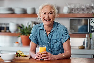 Buy stock photo Shot of a mature woman having orange juice with her breakfast in the kitchen at home