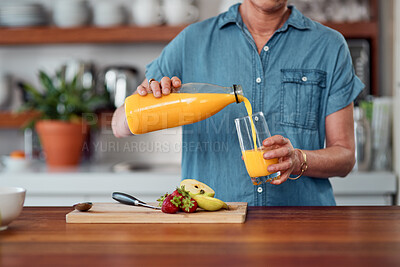 Buy stock photo Shot of an unrecognisable woman pouring orange juice while preparing breakfast in the kitchen at home
