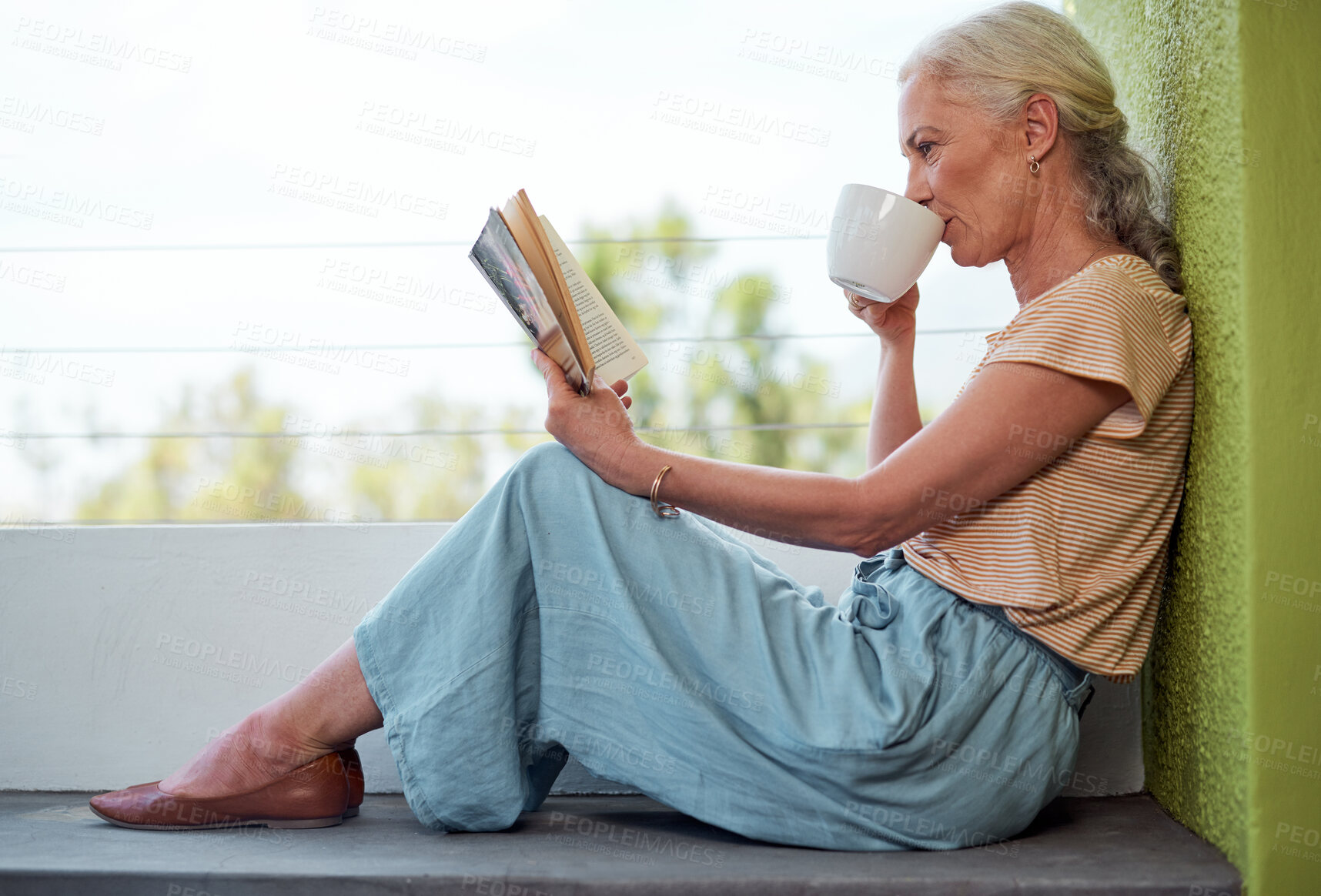 Buy stock photo Senior woman, tea and reading in retirement for relax, learning and wellness in morning on weekend. Elderly person, coffee and book on balcony of home for knowledge, storytelling and hobby with cup