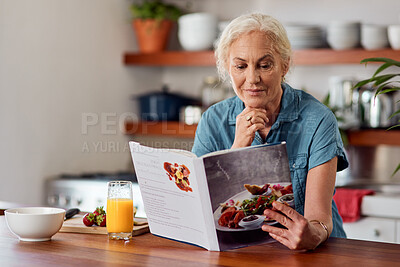 Buy stock photo Shot of a mature woman reading a book while preparing breakfast at home