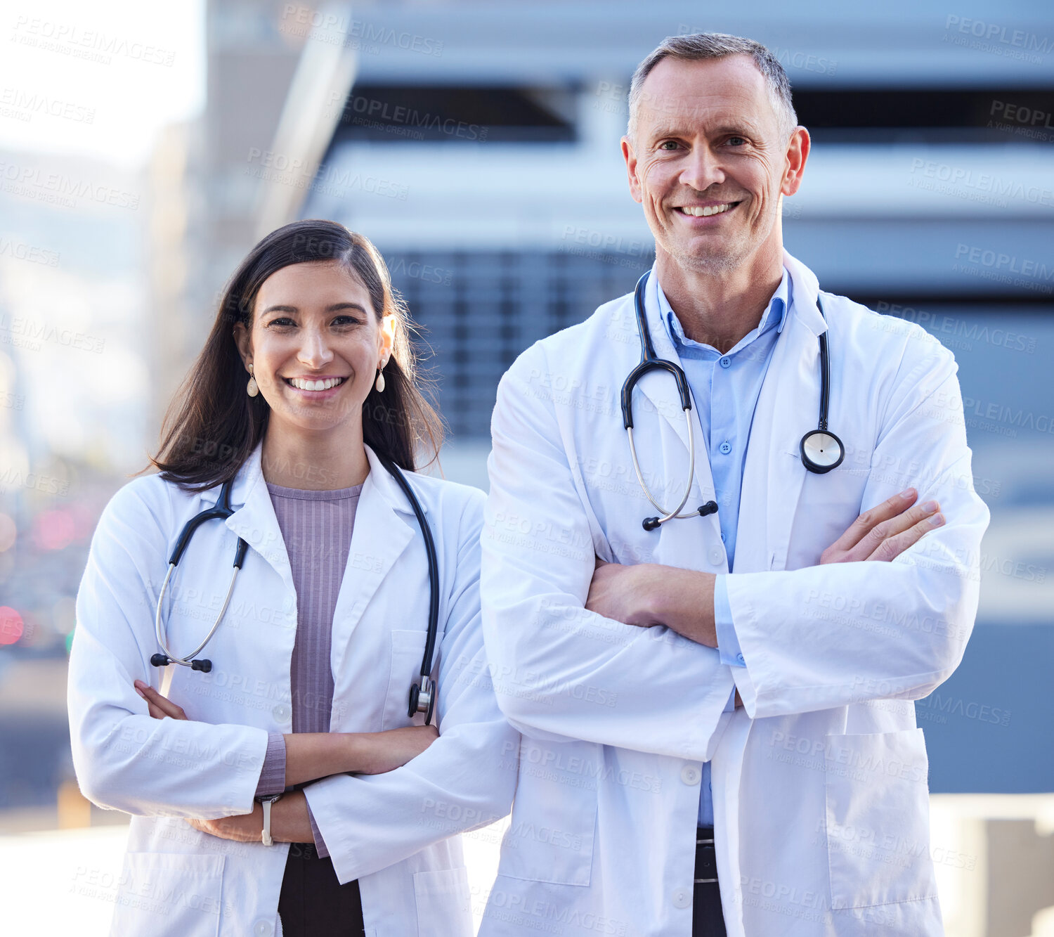Buy stock photo Man, woman and doctors or portrait with arms crossed fpr teamwork by hospital building, confidence or healthcare. Medical, staff and face with stethoscope together for research, partnership or pride