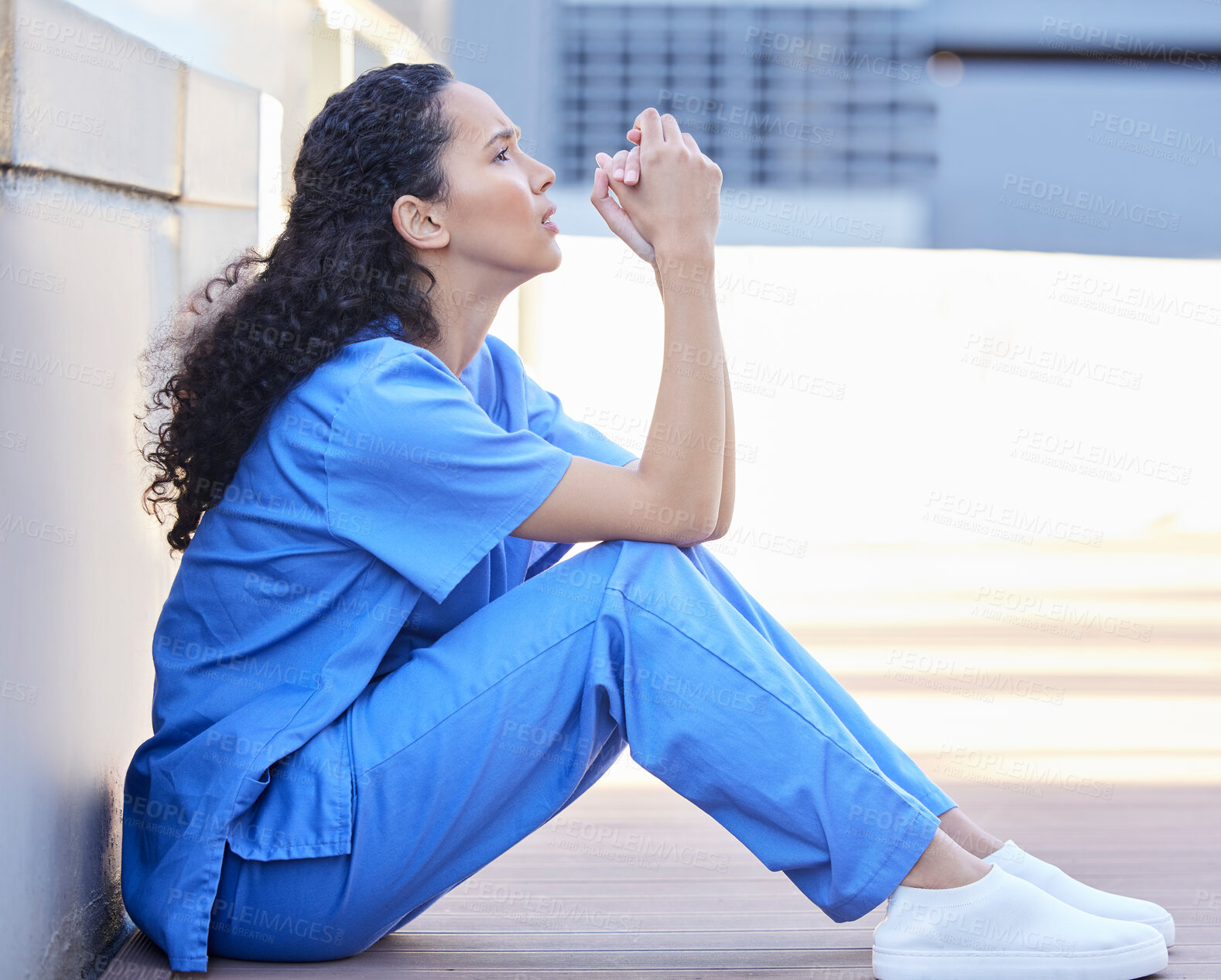 Buy stock photo Shot of a beautiful young doctor looking defeated and stressed outside in the city