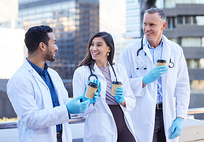 Buy stock photo Shot of doctors enjoying a coffee together while outside in the city