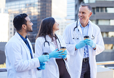Buy stock photo Shot of doctors enjoying a coffee together while outside in the city