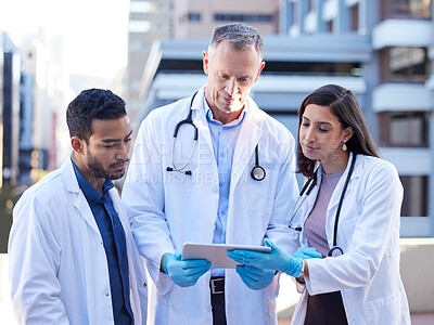 Buy stock photo Shot of doctors using a digital tablet while outside in the city