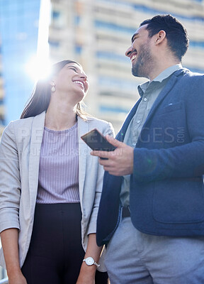 Buy stock photo Shot of two young businesspeople using a smartphone together