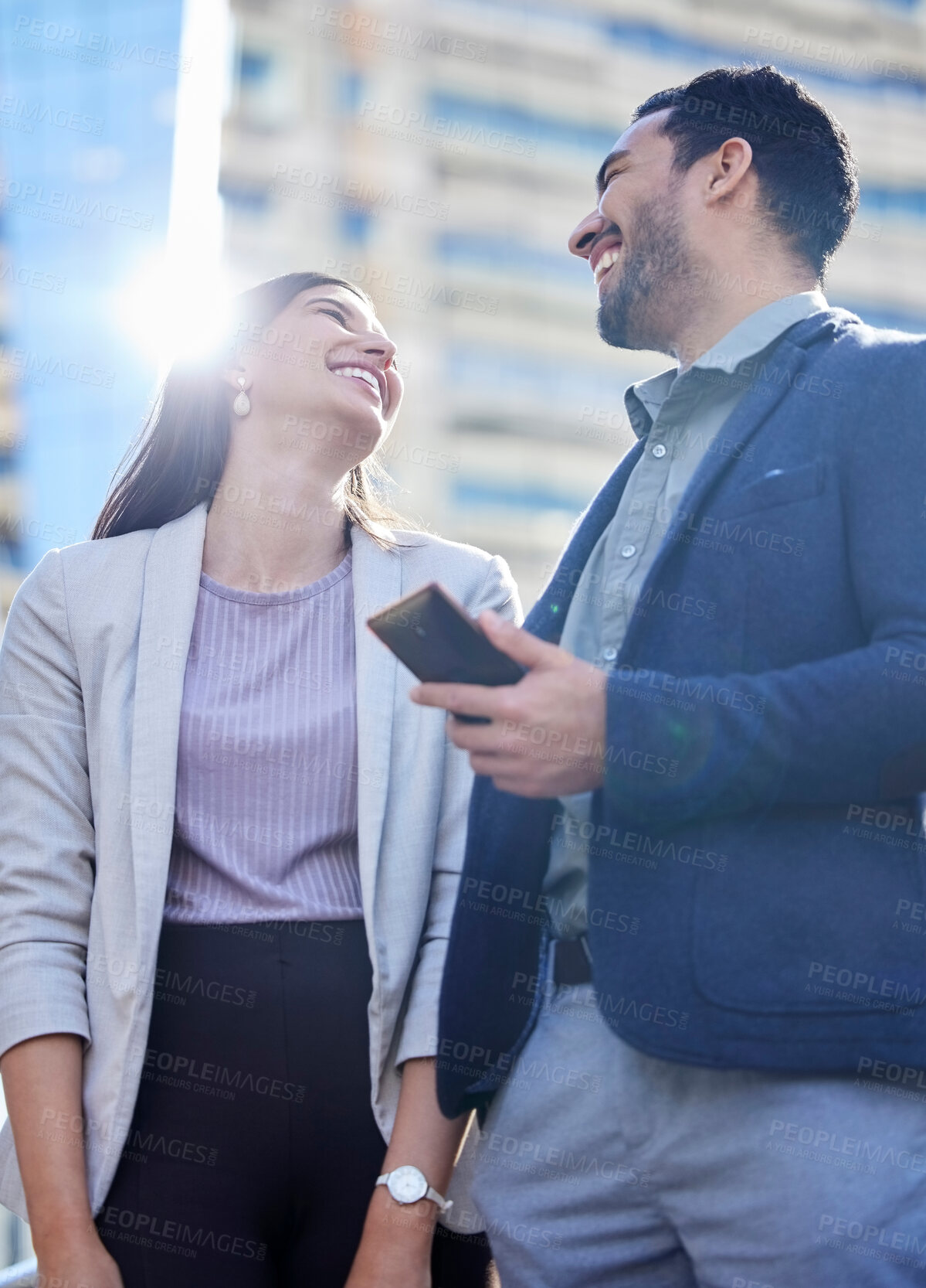 Buy stock photo Shot of two young businesspeople using a smartphone together