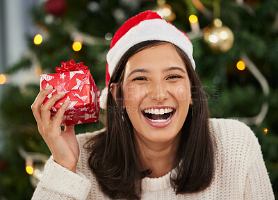 Buy stock photo Shot of a young woman holding a gift box at home during Christmas time
