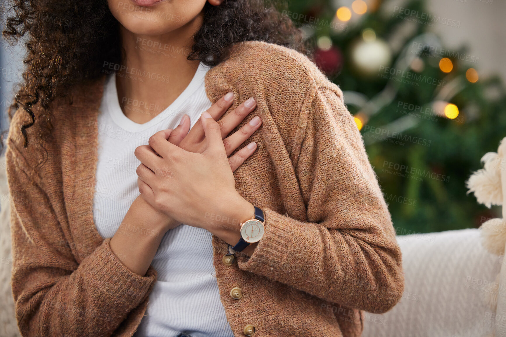 Buy stock photo Cropped shot of an unrecognizable young woman holding her chest in pain while sitting on her sofa on Christmas