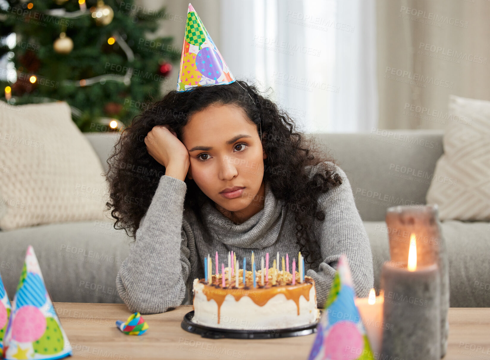 Buy stock photo Shot of a young woman looking unhappy while celebrating her birthday alone at home