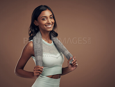 Buy stock photo Shot of an attractive young woman standing alone in the studio and posing with a towel after working out